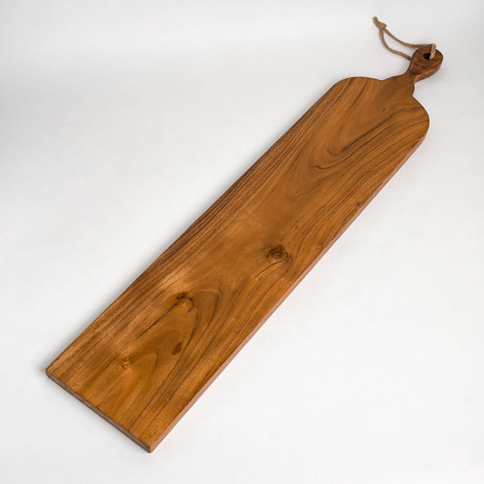 India Handicrafts Inc slim acacia wood cutting board with rope handle, angled view showing grain and knots