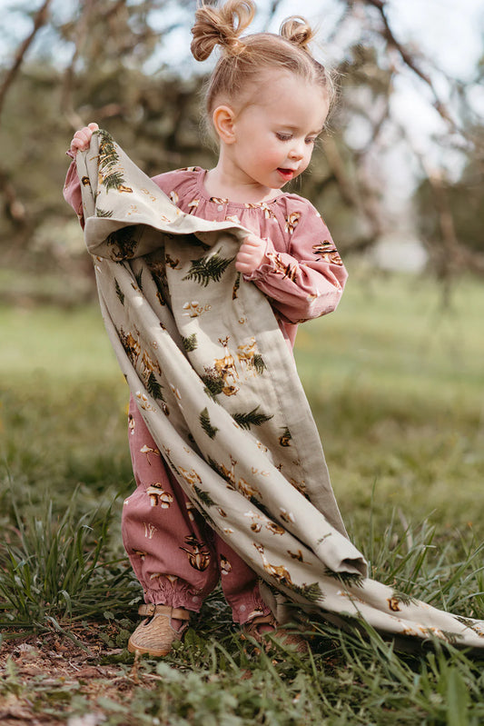 Toddler holding Milkbarn Bamboo Big Lovey with forest animal and fern pattern outdoors