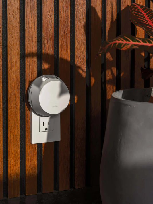 Pura 4" Smart Fragrance Diffuser with black accent band plugged into outlet on wood-slat wall