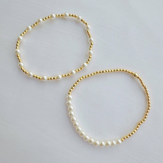Two Ellison+Young Pearls and Gold Stretch Bracelets displayed flat, one with white pearls and one with gold beads