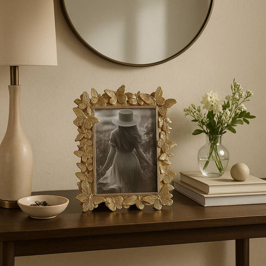Sagebrook Home gold butterfly frame displayed on wooden table with lamp, flowers, and books