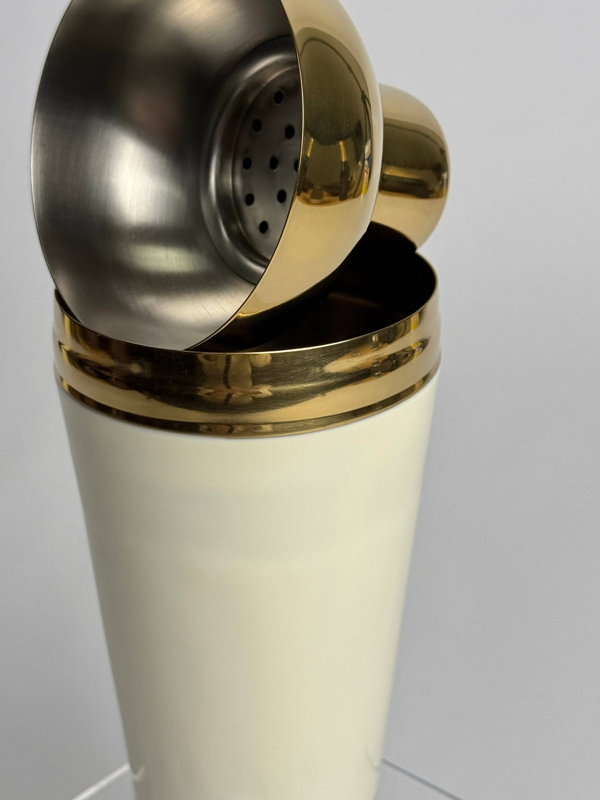 Stainless steel strainer lid detail of India Handicrafts Inc cocktail shaker in cream with brass bands
