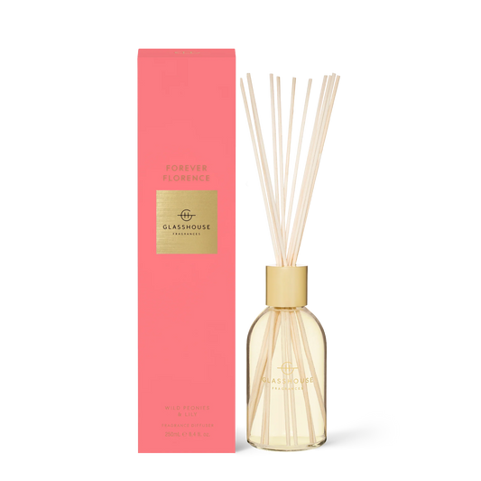 Glasshouse Forever Florence diffuser with gold cap and cream reeds beside coral-pink box