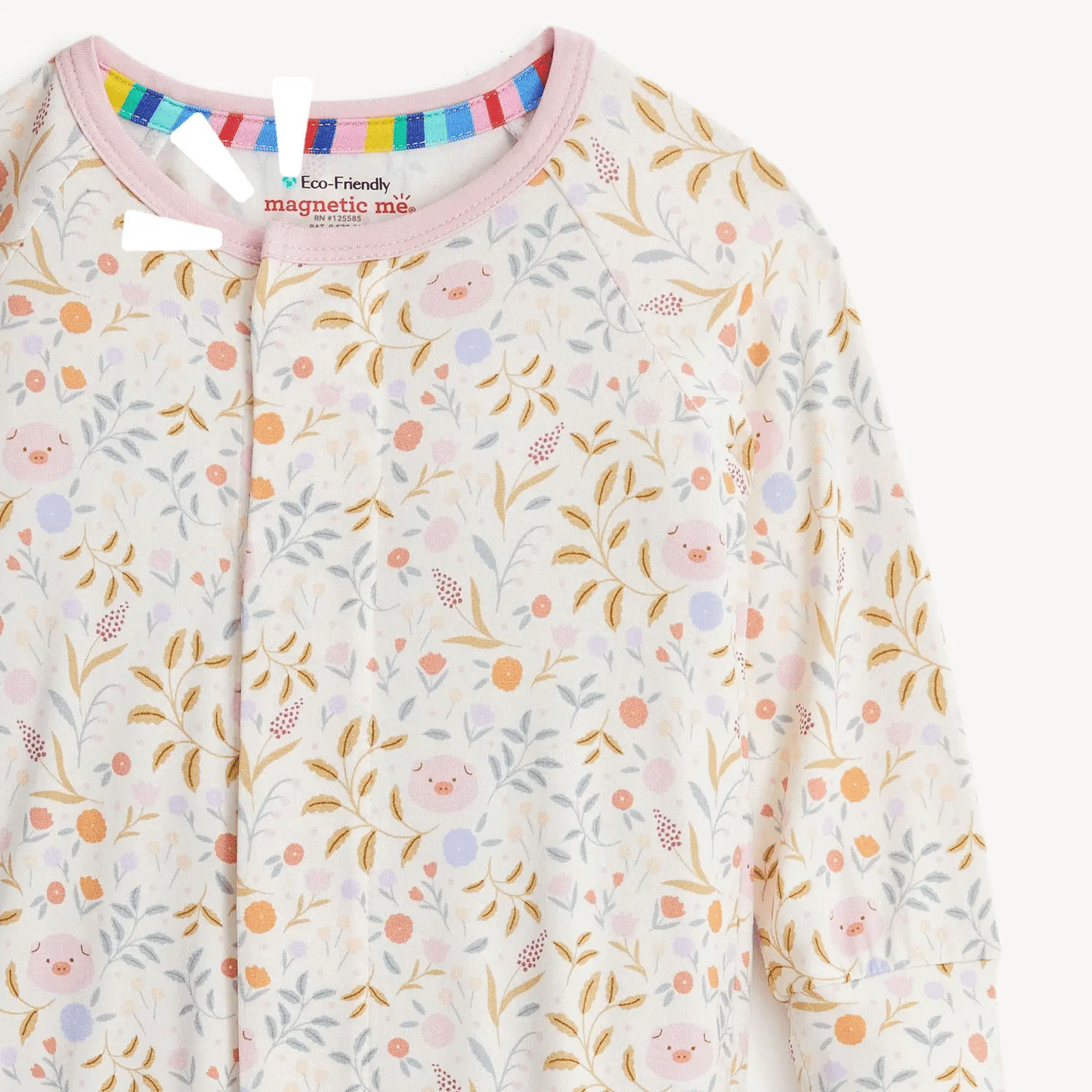 The Magnetic Me "Oinklet" Convertible Coverall from Magnetic Me features a charming floral and piglet pattern, light pink trim, and a colorful striped neckline. Made from sustainable modal fabric, it includes an eco-friendly tag that reads "Eco-Friendly magnetic me.