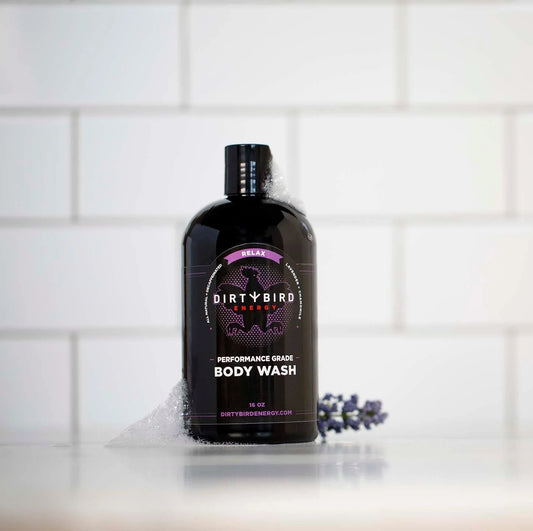 Dirty Bird 16 oz body wash bottle with purple accent label surrounded by white lather and lavender buds