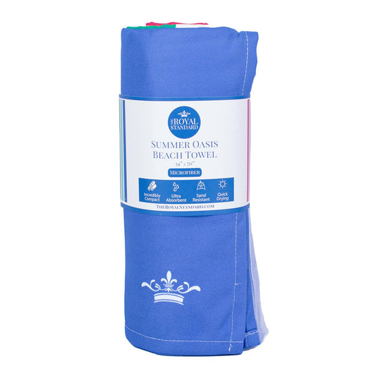 The Royal Standard Summer Oasis Beach Towel rolled in packaging, blue microfiber with white crown logo