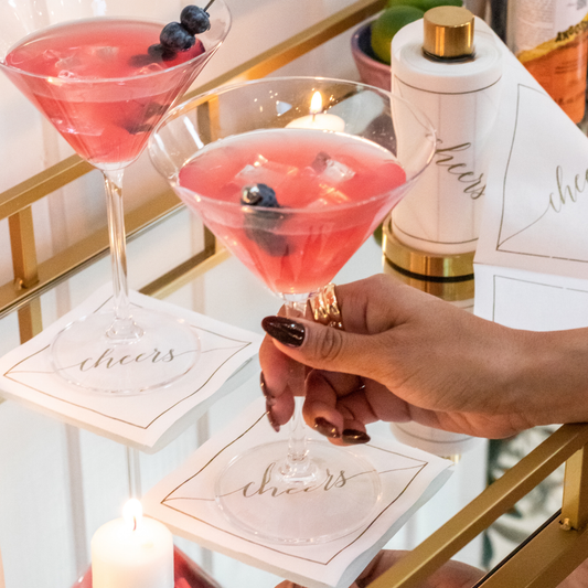 Golden Salute napkins styled at cocktail table with coral drinks and gold accents