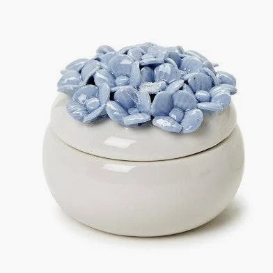 The Two's Company Hydrangea Trinket Box by Two's Company is a small white porcelain jewelry box featuring a lid adorned with glossy light blue ceramic petals, artfully arranged to mimic a hand-painted hydrangea flower.