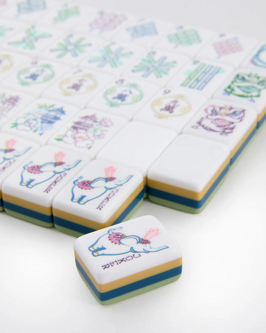 A close-up of the elegant Oh My Mahjong Willow Tiles set by Oh My Mahjong, with most tiles arranged in rows and one tile—adorned with a colorful elephant illustration—placed prominently in the foreground, distinct from the others.