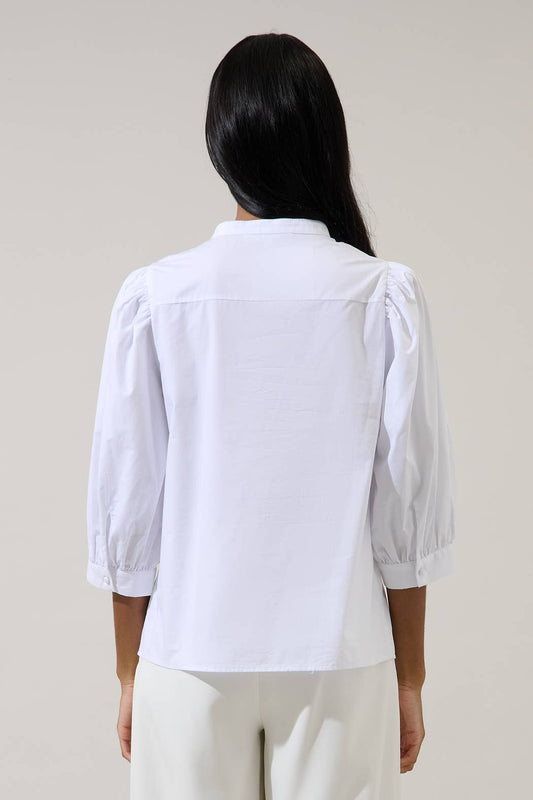 A person with long dark hair, seen from behind, wears the Sugarlips Raveny Button Up Puff Sleeve Shirt in white cotton and matching white pants, standing against a plain light background.