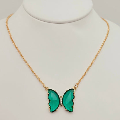 Introducing the Mio Queena - Multicolor Glass Butterfly Pendant Necklace by Mio Queena, featuring a stunning green butterfly pendant accented with small clear stones at its center. Displayed on a white jewelry stand, this hypoallergenic necklace combines elegance and comfort, making it suitable for sensitive skin.
