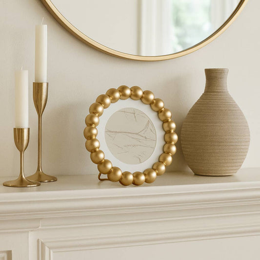 Sagebrook Home gold beaded frame displayed on mantel with gold candlesticks and vase