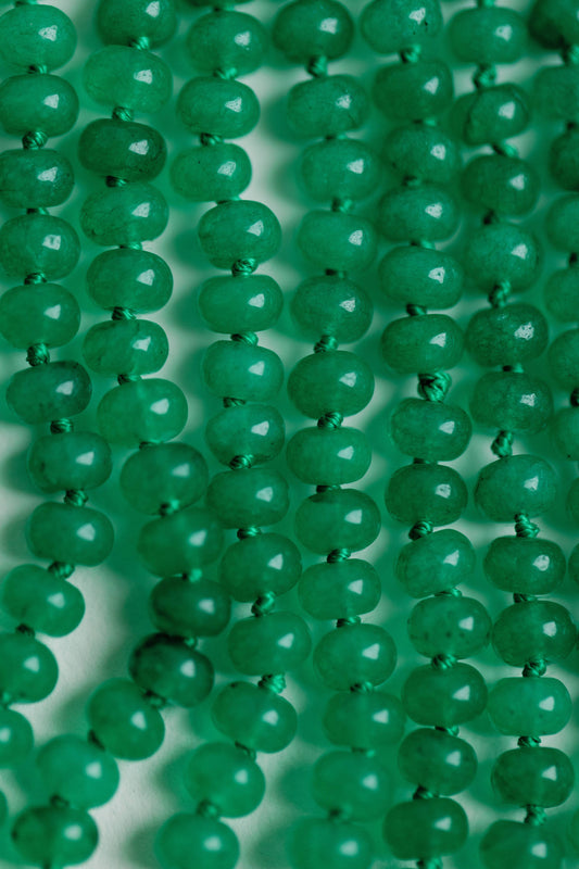 Close-up of genuine jade beads showing green faceted surface and dark threading detail