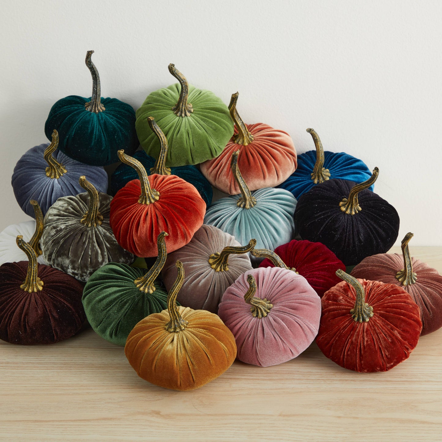 A charming collection of Your Heart’s Content - Pumpkin Small Velvet decor in an array of colors—green, blue, orange, yellow, red, and purple—arranged on a light wooden surface against a white background; ideal for a Valentine’s mantel, autumn table display, or as a thoughtful gift.