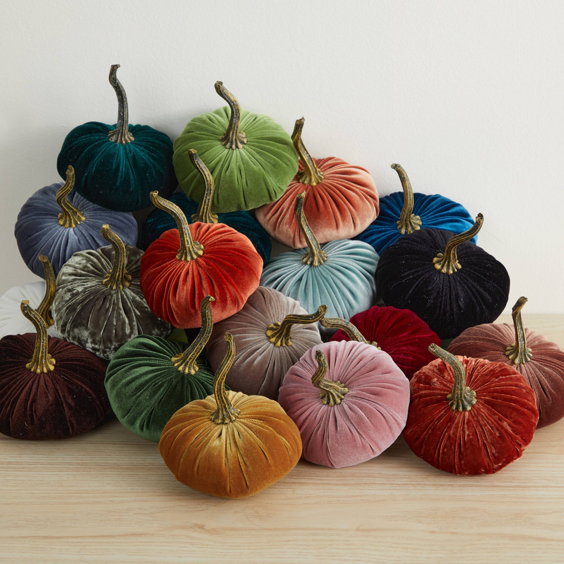 A charming collection of Your Heart’s Content - Pumpkin Small Velvet decor in an array of colors—green, blue, orange, yellow, red, and purple—arranged on a light wooden surface against a white background; ideal for a Valentine’s mantel, autumn table display, or as a thoughtful gift.
