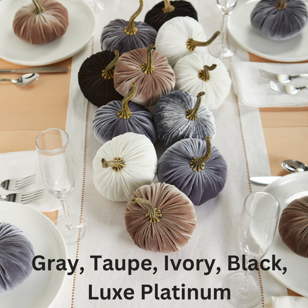 Small velvet pumpkins from Your Heart’s Content in shades of gray, taupe, ivory, black, and luxe platinum are artfully arranged on a white table runner between place settings and glasses to create a stunning Thanksgiving centerpiece. Text: “Your Heart’s Content - Pumpkin Small Velvet: Gray, Taupe, Ivory, Black, Luxe Platinum.”.