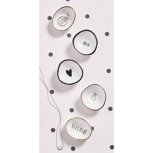 Five Santa Barbara Design Studio ring dishes with varied designs including ring, heart, and 'xo' text, gold and black trim