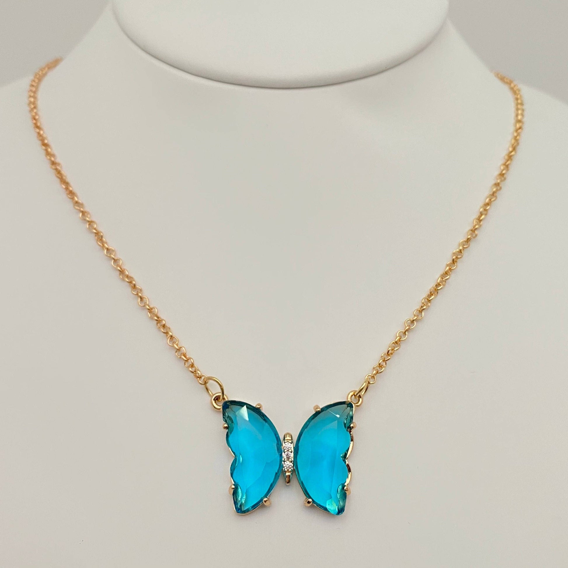 Mio Queena - Multicolor Glass Butterfly Pendant Necklace by Mio Queena, featuring a delicate butterfly pendant with two vibrant wings and a small central accent. This hypoallergenic necklace is beautifully presented on a white jewelry stand.