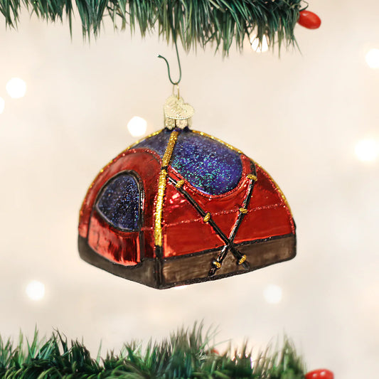 The Old World Christmas Dome Tent Ornament by Old World Christmas, featuring a shiny red and purple glass design with gold trim, hangs from a green Christmas tree branch amid softly blurred white lights—making it the perfect camping gift for any enthusiast.