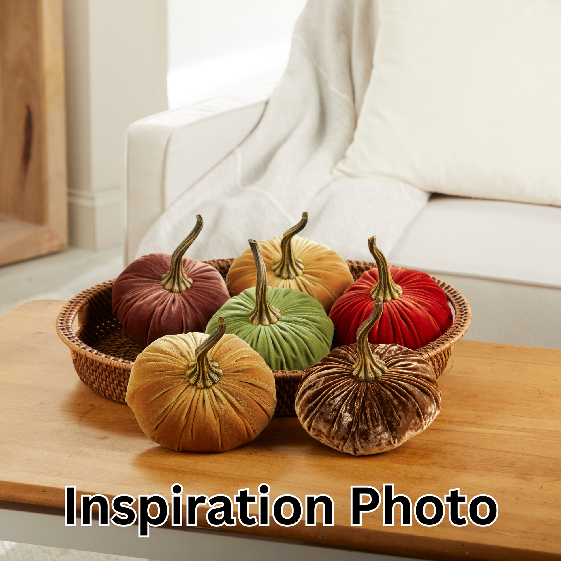 A woven tray displays six autumn-hued fabric pumpkins, including the “Your Heart’s Content - Pumpkin Large Velvet” by Your Heart’s Content, arranged on a wooden table before a white sofa with cushions. This handcrafted decor creates an inviting Thanksgiving centerpiece. The words “Inspiration Photo” appear at the bottom.