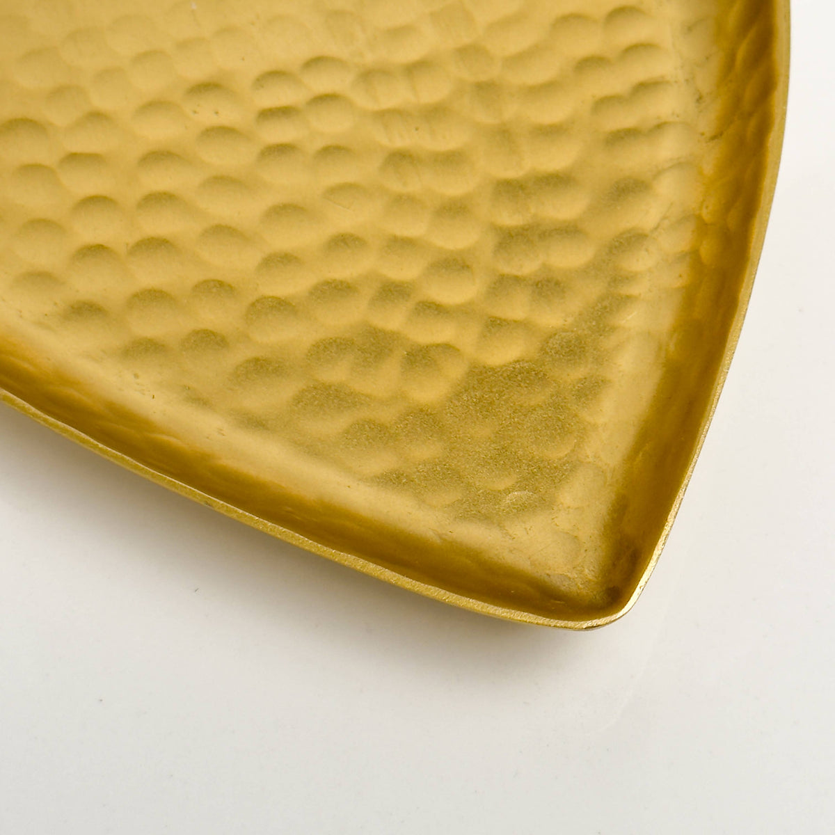 Hammered surface detail of gold heart tray at angle