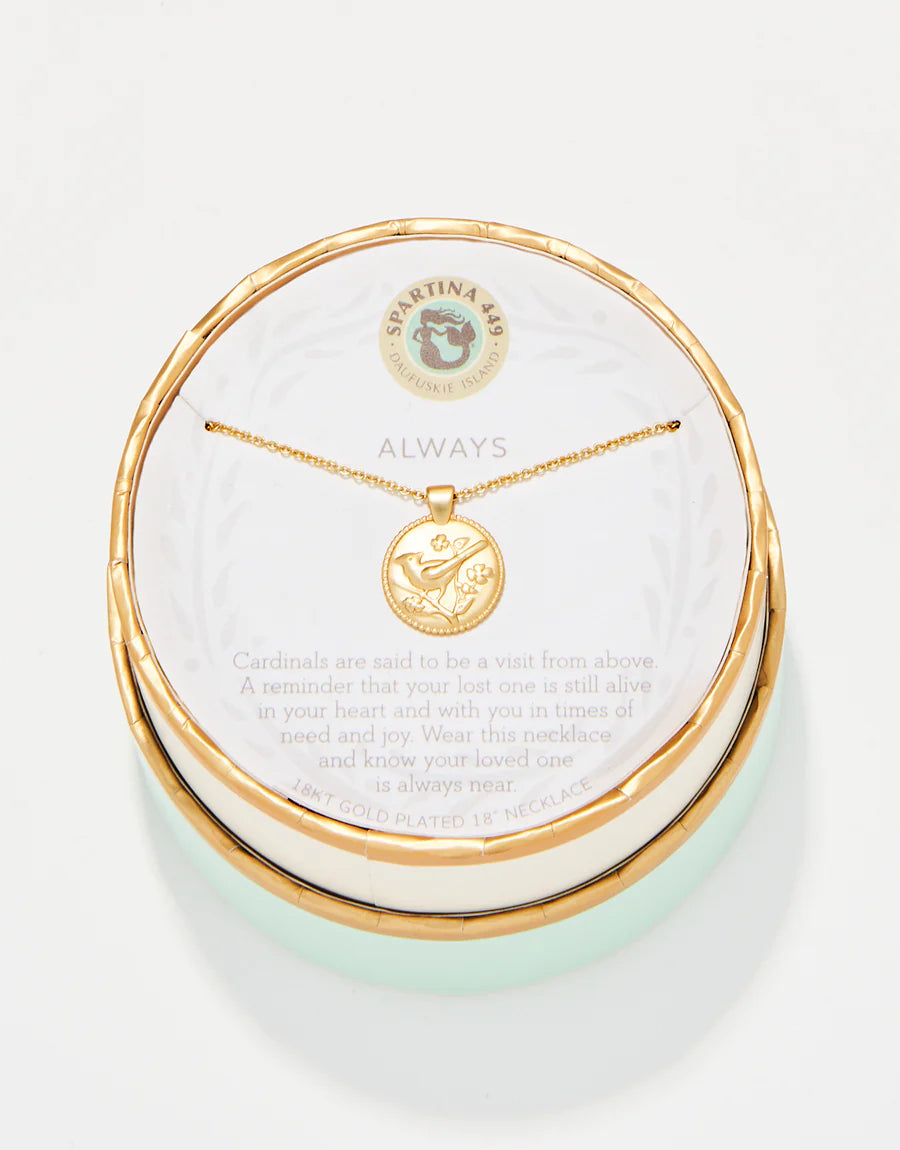 The Spartina Sea La Vie Always/Cardinal necklace features a gold-plated cardinal charm on a round pendant, beautifully presented in a matching round box. The packaging includes an explanation that cardinals represent visits from lost loved ones, making this necklace a meaningful remembrance gift. The brand name "Spartina" is displayed at the top of the packaging.