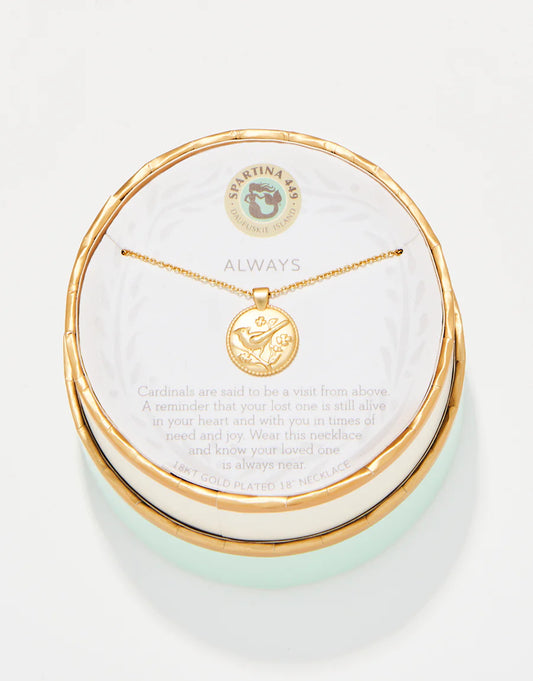 The Spartina Sea La Vie Always/Cardinal necklace features a gold-plated cardinal charm on a round pendant, beautifully presented in a matching round box. The packaging includes an explanation that cardinals represent visits from lost loved ones, making this necklace a meaningful remembrance gift. The brand name "Spartina" is displayed at the top of the packaging.
