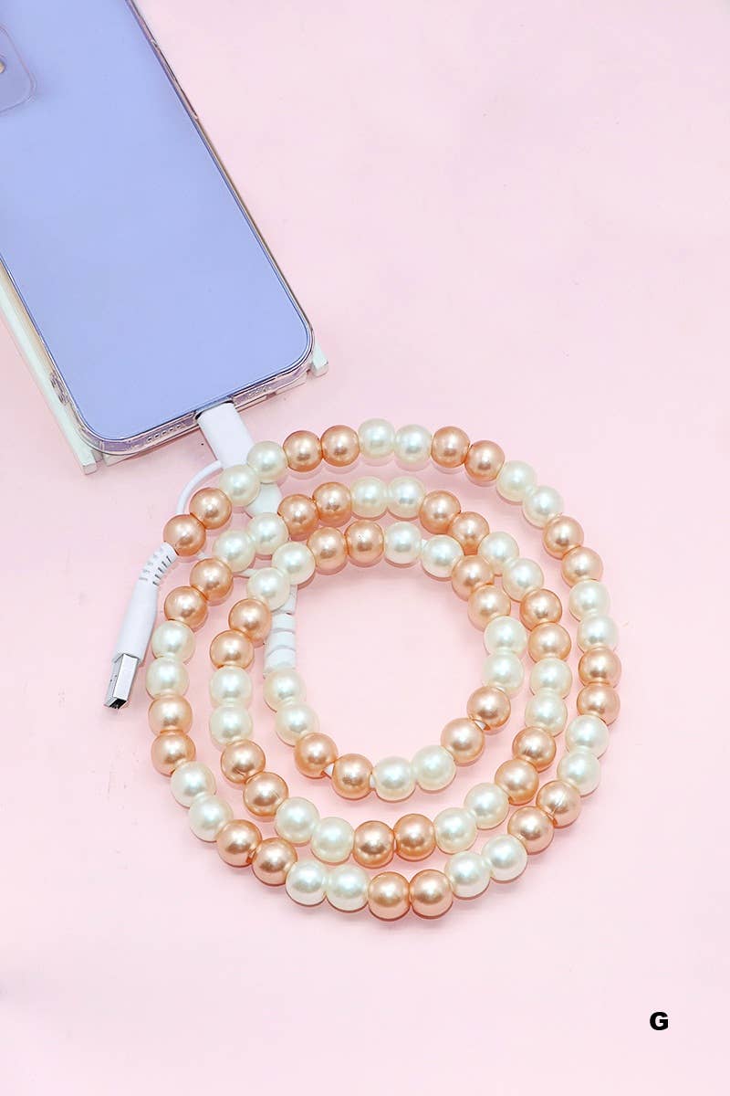 A lavender phone is paired with the 42POPS Beaded Dual USB Fast Charging Cable by 42POPS, decorated with alternating gold and white pearl-like beads and coiled on a light pink surface.