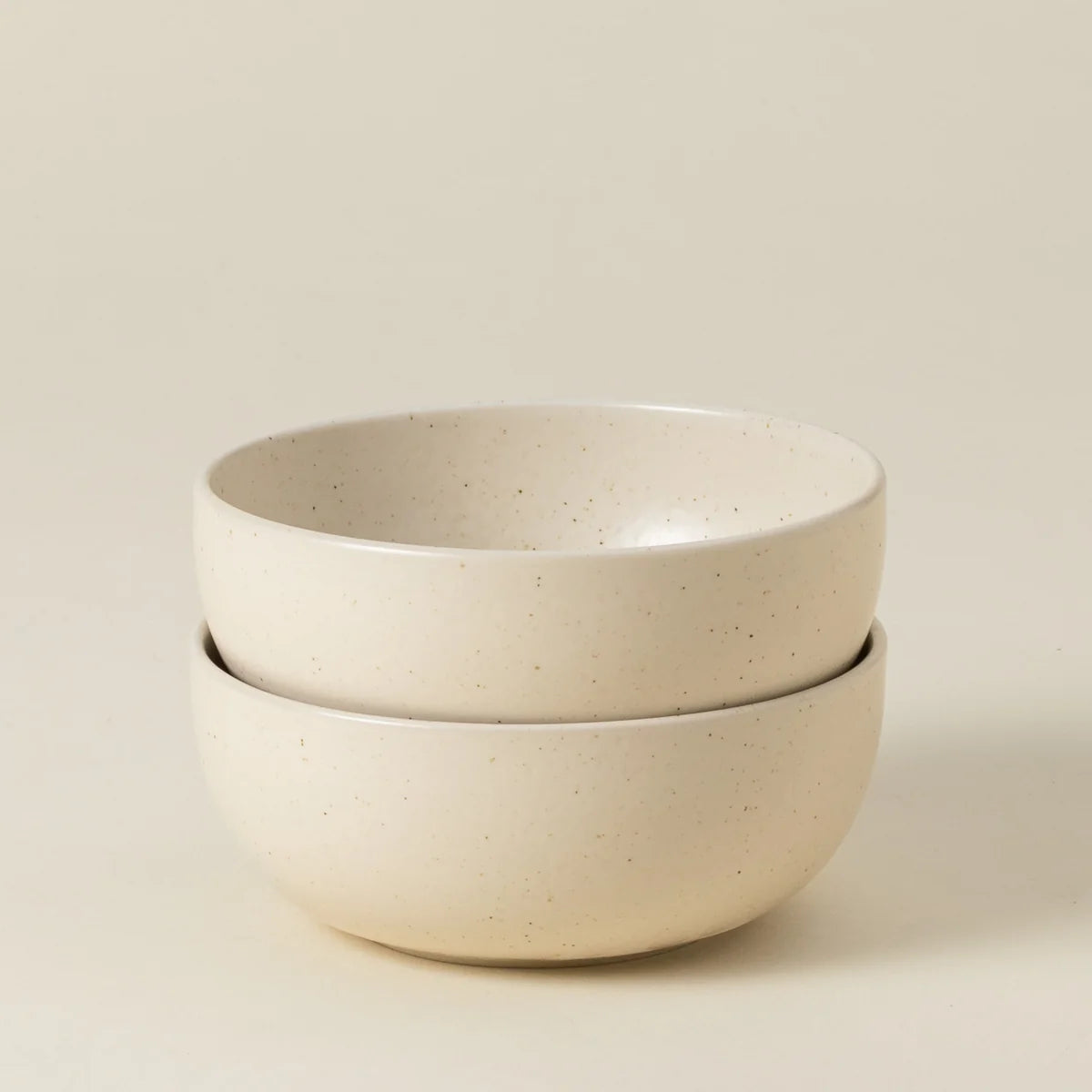 Two stacked Casafina “Pacifica - Vanilla Beige” ceramic cereal bowls, featuring a smooth, slightly speckled surface, are displayed against a plain, light background.