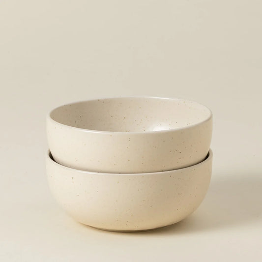 Two stacked Casafina “Pacifica - Vanilla Beige” ceramic cereal bowls, featuring a smooth, slightly speckled surface, are displayed against a plain, light background.