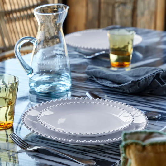 Costa Nova Pearl white dinner plate with beaded rim edge, styled at a table setting with blue napkins and glassware