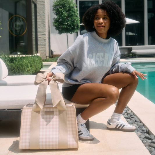 Latte gingham tote worn by woman poolside showing front gingham pattern and bow detail