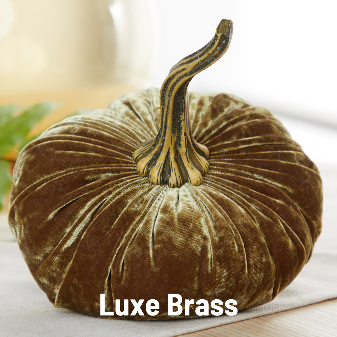 A large velvet pumpkin by Your Heart’s Content, featuring a brass-colored stem, rests on a table as an inviting Thanksgiving centerpiece. The text “Your Heart’s Content - Pumpkin Large Velvet” appears at the bottom of the image.