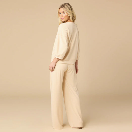 Woman wearing warm sand Softies terry cropped sleeve crew neck and wide leg pants, back view