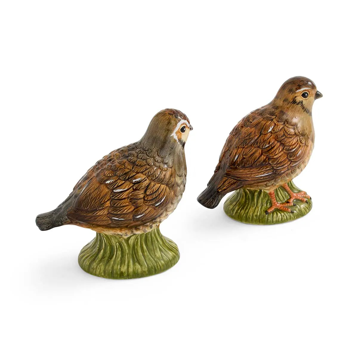 Two ceramic quail figurines, painted in brown with white and black accents, stand on green grassy bases. This delightful Spode Woodland Quail Salt & Pepper set by Spode adds a touch of the outdoors to your decorative tableware collection.