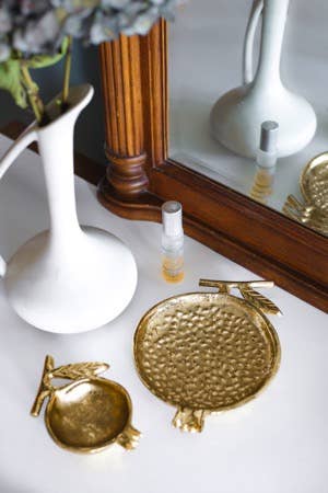 Gold Pomegranate Bowl styled on shelf with home décor and smaller pomegranate bowl