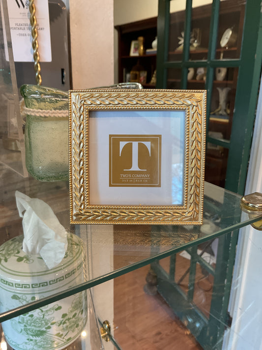 Two's Company gold mini frame with ornate border and blue mat, square format displayed on glass shelf