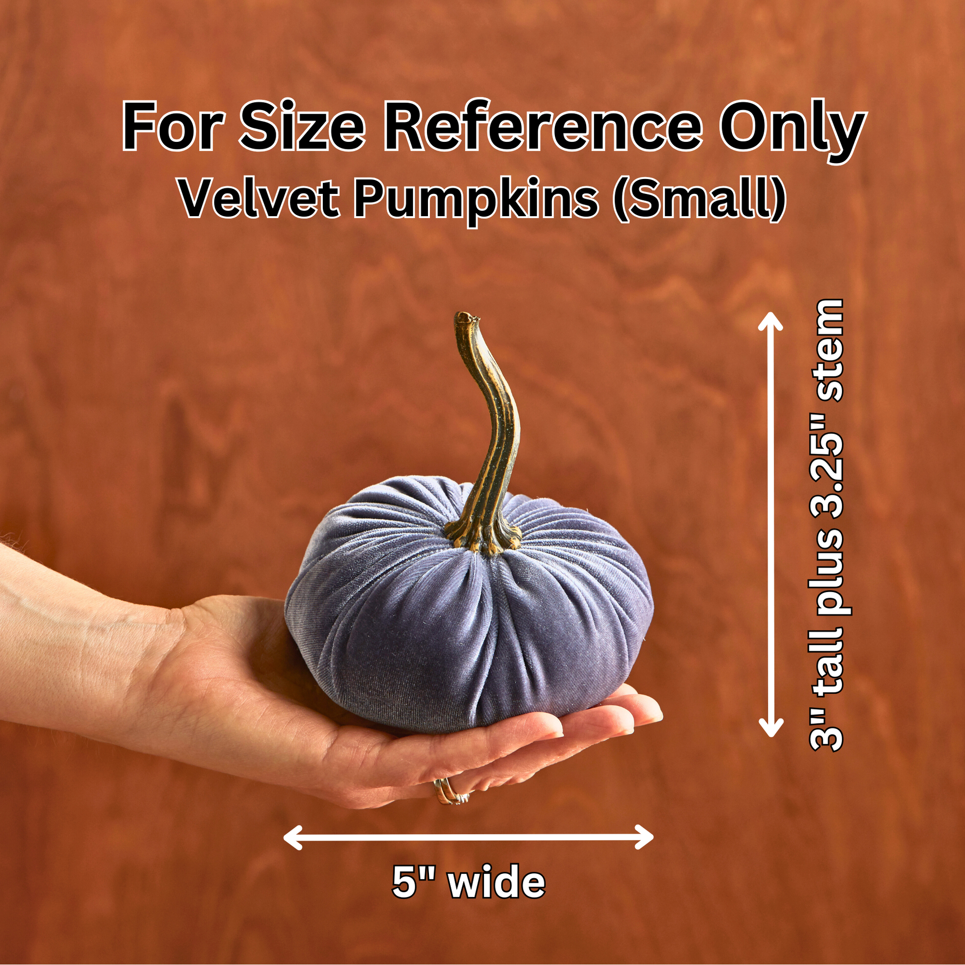 A hand holds the “Your Heart’s Content - Pumpkin Small Velvet,” a stylish blue velvet pumpkin featuring a long 3.25-inch stem, perfect for a Valentine’s mantel or autumn table décor. Measuring 5 inches wide and 3 inches tall (plus stem), this charming piece by Your Heart’s Content is displayed against a brown wood background for size reference.