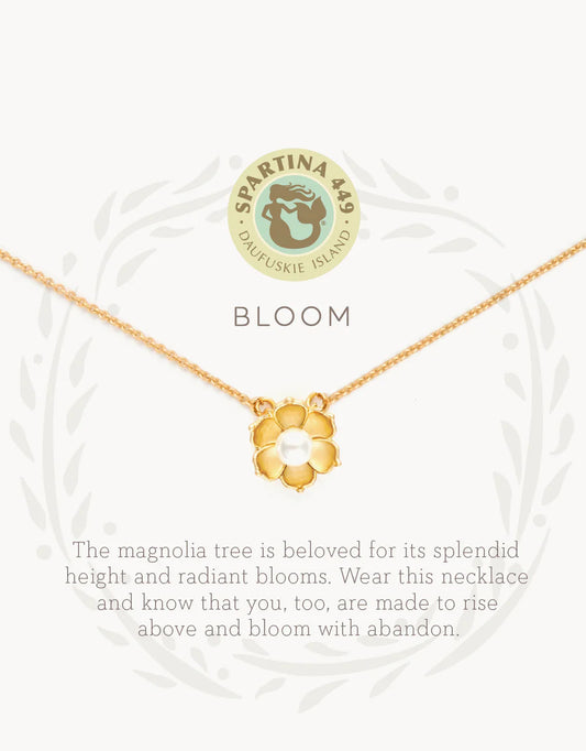 The Spartina Sea La Vie Bloom Necklace features a gold magnolia flower pendant on a delicate chain, displayed above the word "BLOOM" and an uplifting message about the magnolia tree's beauty and symbolism of rising above. This inspirational jewelry piece from Spartina captures both elegance and meaningful encouragement—a beautiful magnolia necklace designed to remind you to shine. The Spartina logo appears at the top.