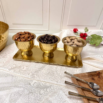 Gold aluminum pedestal bowl set with hammered texture holding assorted snacks on tray