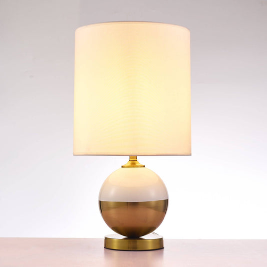 Senato table lamp lit, showing warm cream glow through white fabric shade and illuminated sphere base