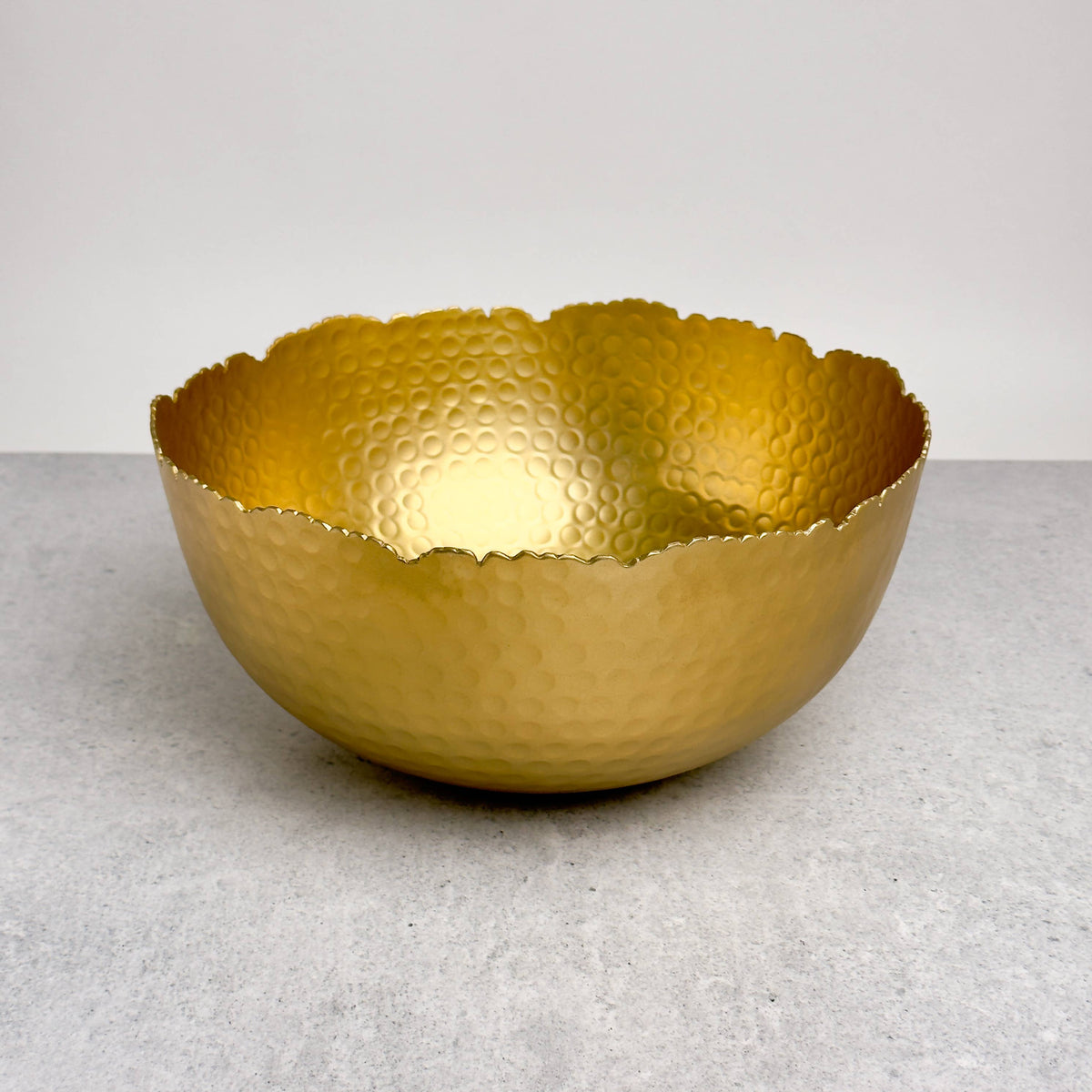India Handicrafts Inc Large Gilded Hammered Bowl three-quarter view with wavy rim and textured gold surface