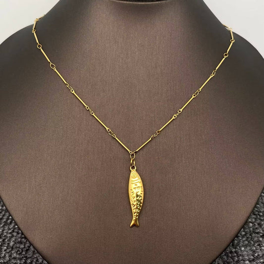 The Mio Queena - 18K Gold Plated Stainless Steel Fish Necklace by Mio Queena is displayed on a black bust, showcasing a fish-shaped pendant with textured details hanging at the center.