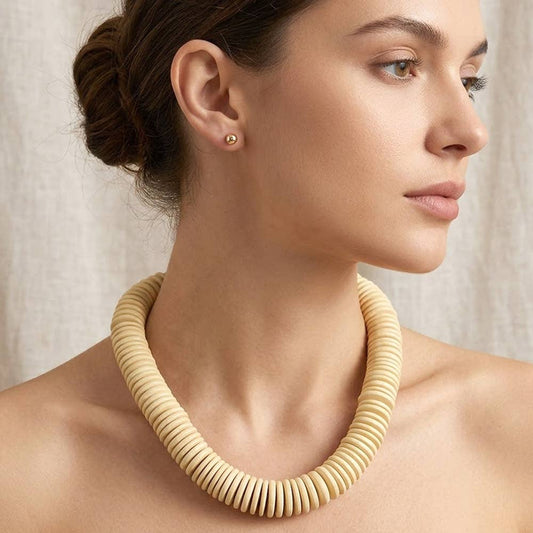 Chunky wooden disc beaded statement necklace in natural wood worn as collar, styled on model in profile