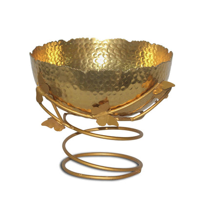 Gold hammered bowl with scalloped rim resting on decorative metal stand with curved wire base