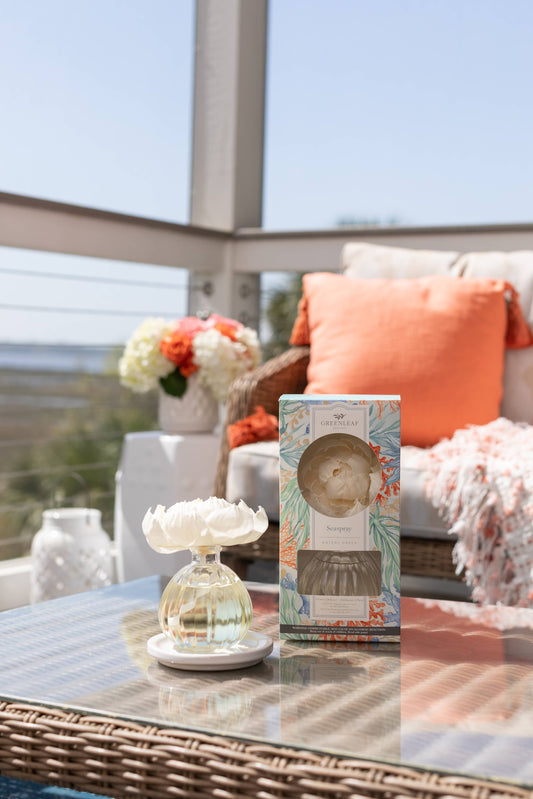 Greenleaf Gifts Seaspray Flower Diffuser with cream flower-shaped top on white pedestal base, displayed with packaging box on coastal patio table