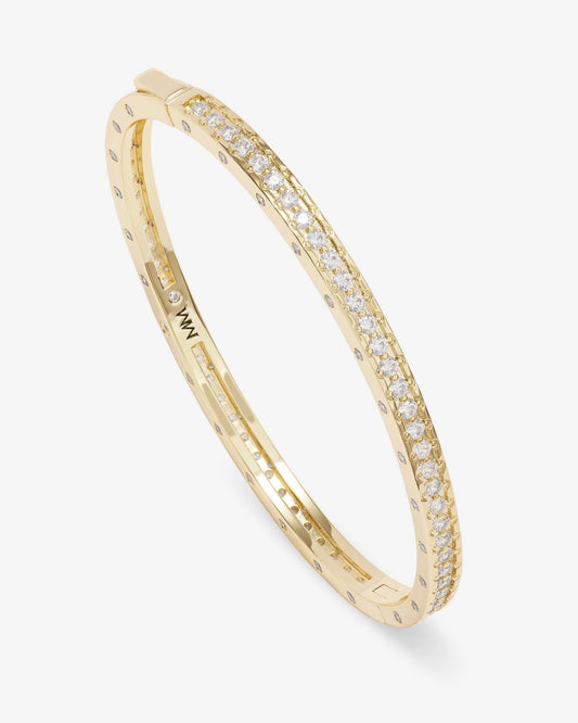 The Melinda Maria Ashley Pave Cuff Gold by Melinda Maria is an oval gold cuff bracelet featuring a row of sparkling pavé simulated diamonds along its top edge, displayed at an angle on a plain white background.