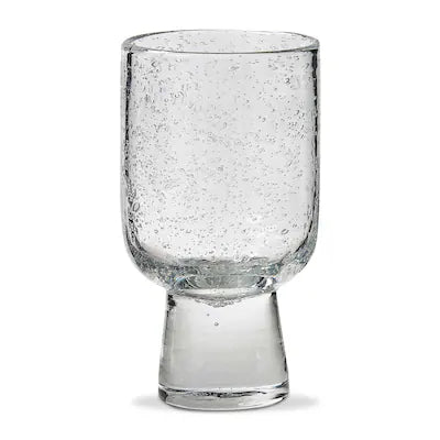 The Tag "Bubble" Footed Juice Glass by Tag features a clear, textured surface adorned with visible air bubbles and is designed with a thick, sturdy base.