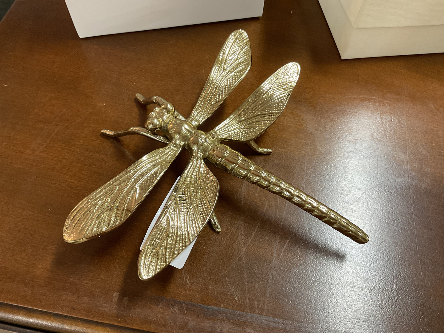 Elevate your decor with the Two’s Company Gold Flora and Fauna Nature Decor—a refined brass dragonfly sculpture with gracefully outstretched wings, poised on a polished wooden base beside a sleek white box. This captivating accent from Two’s Company is perfect for butterfly and dragonfly enthusiasts, effortlessly complementing both classic and contemporary spaces.