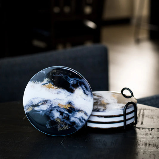 Lynn & Liana ceramic resin coasters in use on dark table, featuring navy and white marble pattern with gold accents
